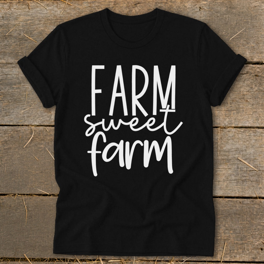Black t-shirt with white text "FARM sweet farm" on a wooden background.