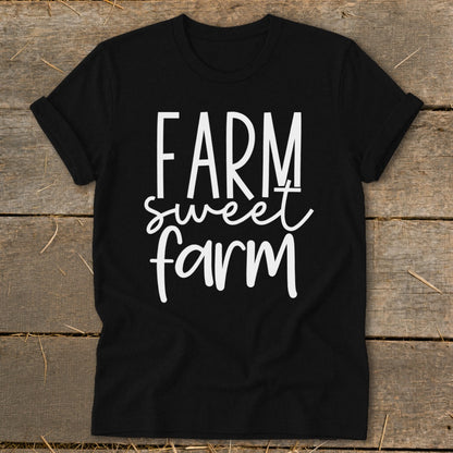 Black t-shirt with white text "FARM sweet farm" on a wooden background.