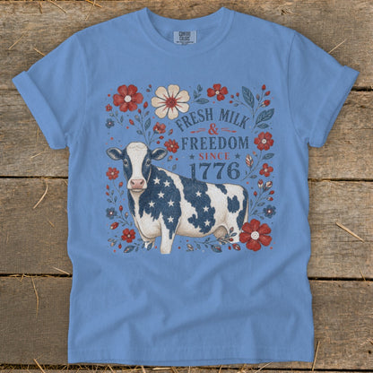 Cow with American flag pattern on a t-shirt with text "Fresh Milk & Freedom Since 1776".
