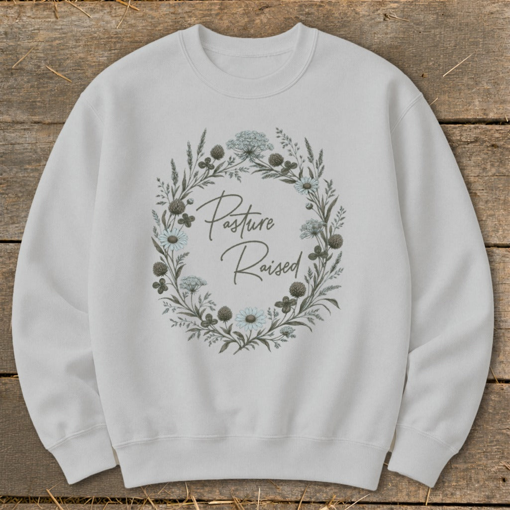 White sweatshirt with a floral wreath graphic and "Pasture Raised" text.