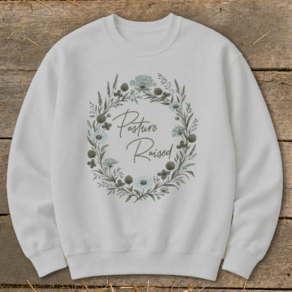 White sweatshirt with a floral wreath graphic and "Pasture Raised" text.