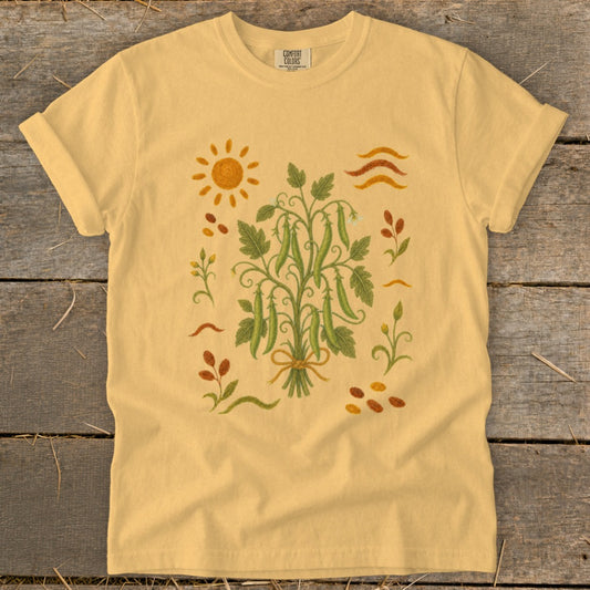 Yellow t-shirt with embroidered peas, sun, and floral accents.