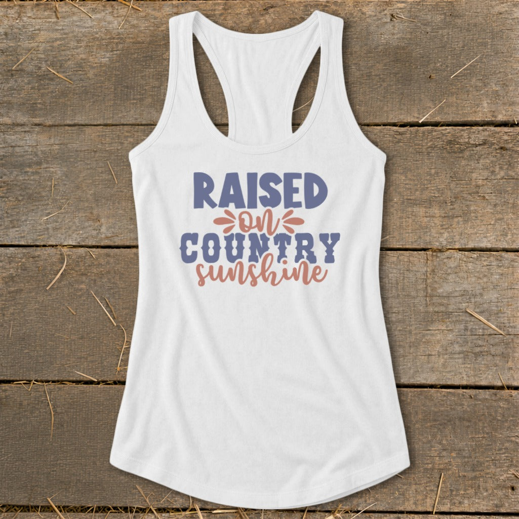 White tank top with "Raised on Country Sunshine" text graphic.