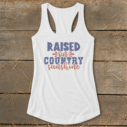 White tank top with "Raised on Country Sunshine" text graphic.