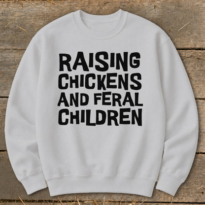 White sweatshirt with black text reading "Raising Chickens and Feral Children".