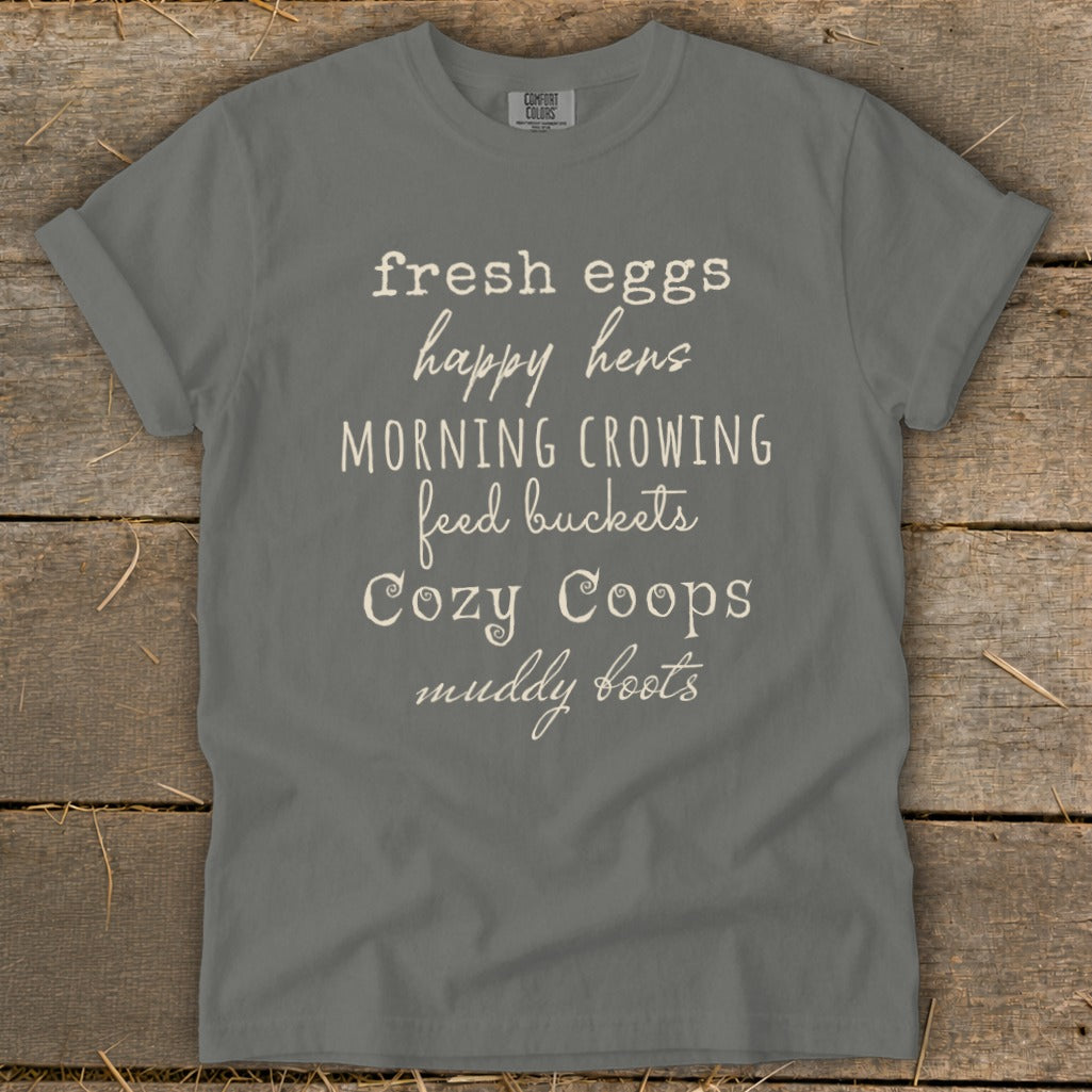 Gray t-shirt with "fresh eggs, happy hens, morning crowing, feed buckets, cozy coops, muddy boots" text.