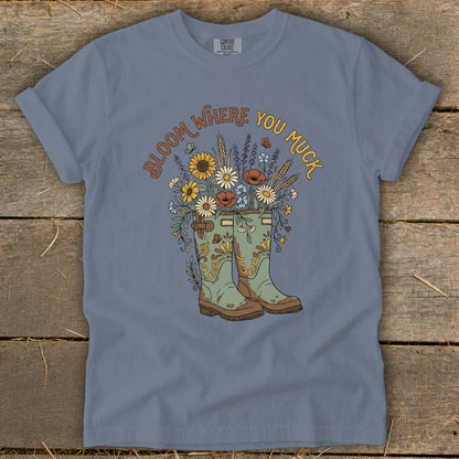 T-shirt with "Bloom Where You Muck" text and gardening boot floral illustration.