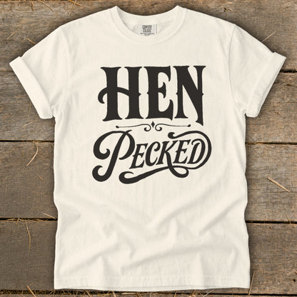 Cream t-shirt with black text reading "HEN PECKED" in decorative fonts.