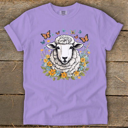 Sheep illustration surrounded by butterflies and colorful flowers on a lavender t-shirt.