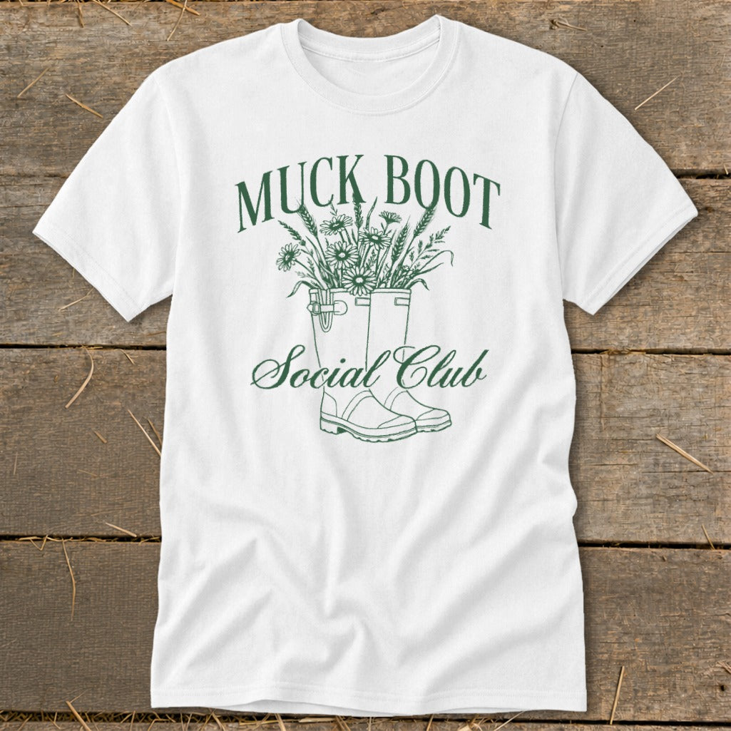 White t-shirt with green "Muck Boot Social Club" text and illustration of boots with flowers.