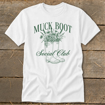 White t-shirt with green "Muck Boot Social Club" text and illustration of boots with flowers.