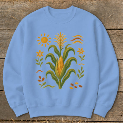 Light blue sweatshirt with a corn stalk, sun, and floral motifs design.