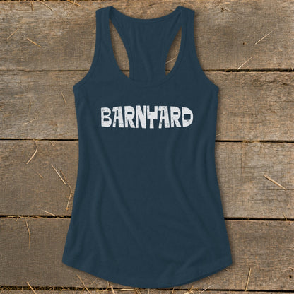 Dark blue racerback tank top featuring the distressed white text "BARNYARD" centered on the chest, laid flat on a rustic wooden surface.