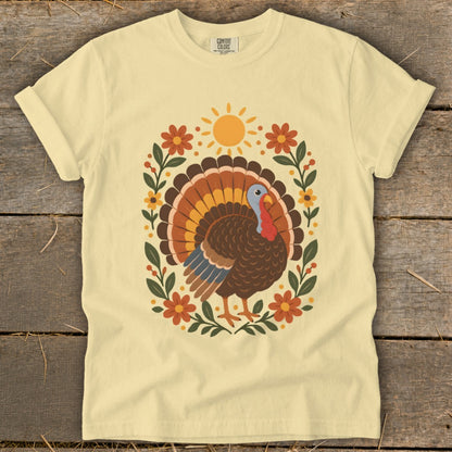 Yellow t-shirt with a colorful turkey design framed by flowers and leaves.