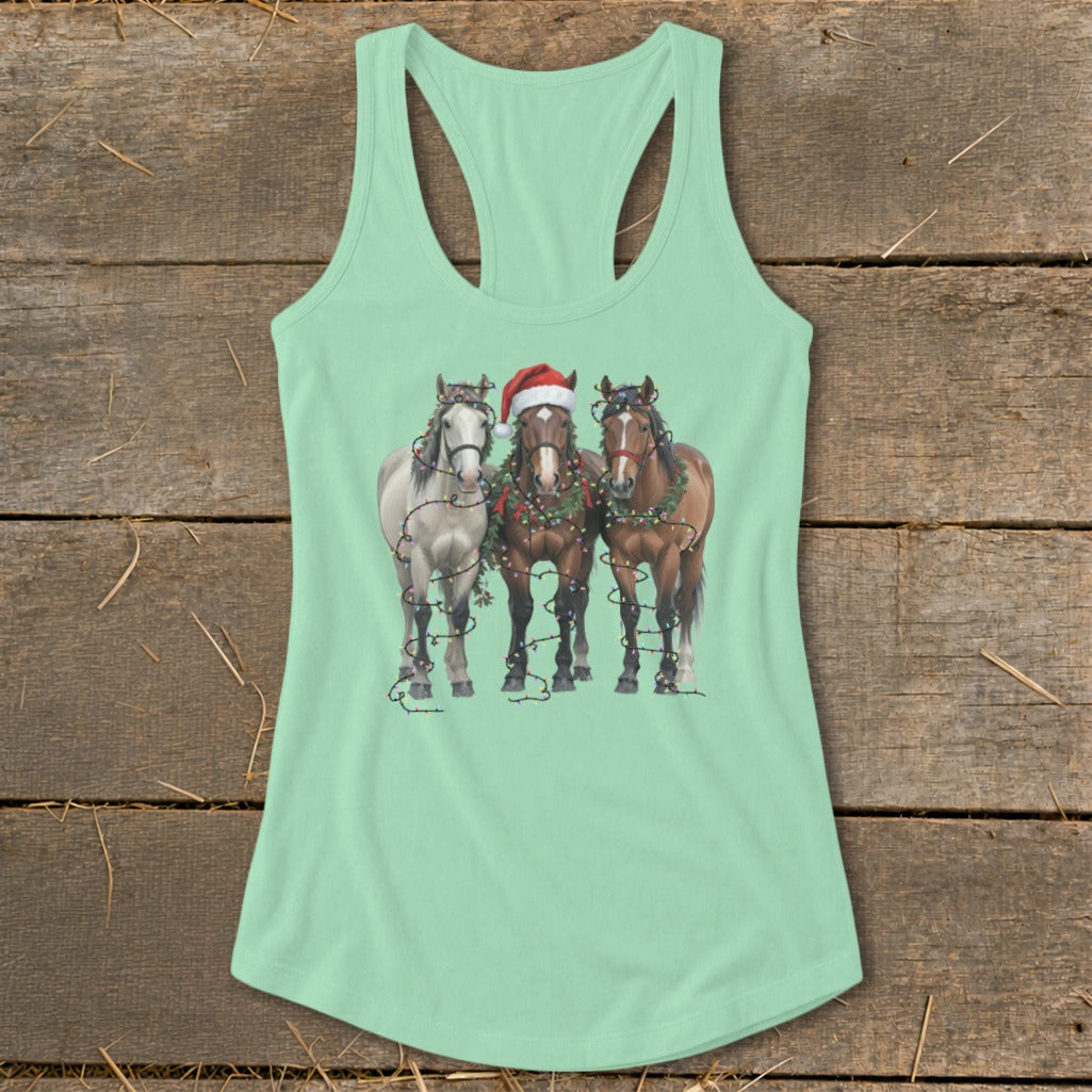 Three horses decorated with Christmas lights and one wearing a Santa hat.