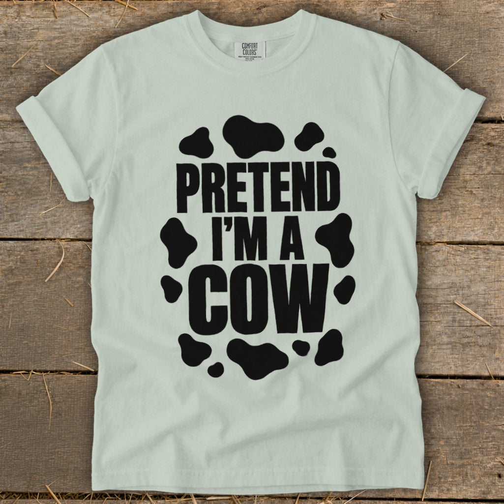 Light blue t-shirt with black text and cow spots reading "PRETEND I'M A COW".