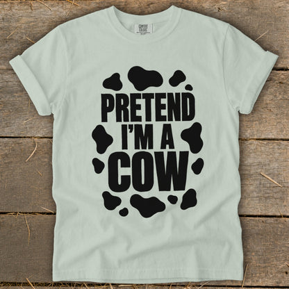 Light blue t-shirt with black text and cow spots reading "PRETEND I'M A COW".