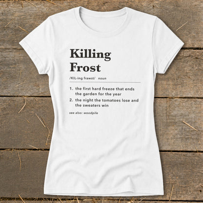 A white short-sleeved t-shirt lies flat on a wooden surface, featuring black text defining "Killing Frost."