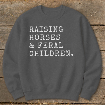 Charcoal crewneck sweatshirt with white text "RAISING HORSES & FERAL CHILDREN."
