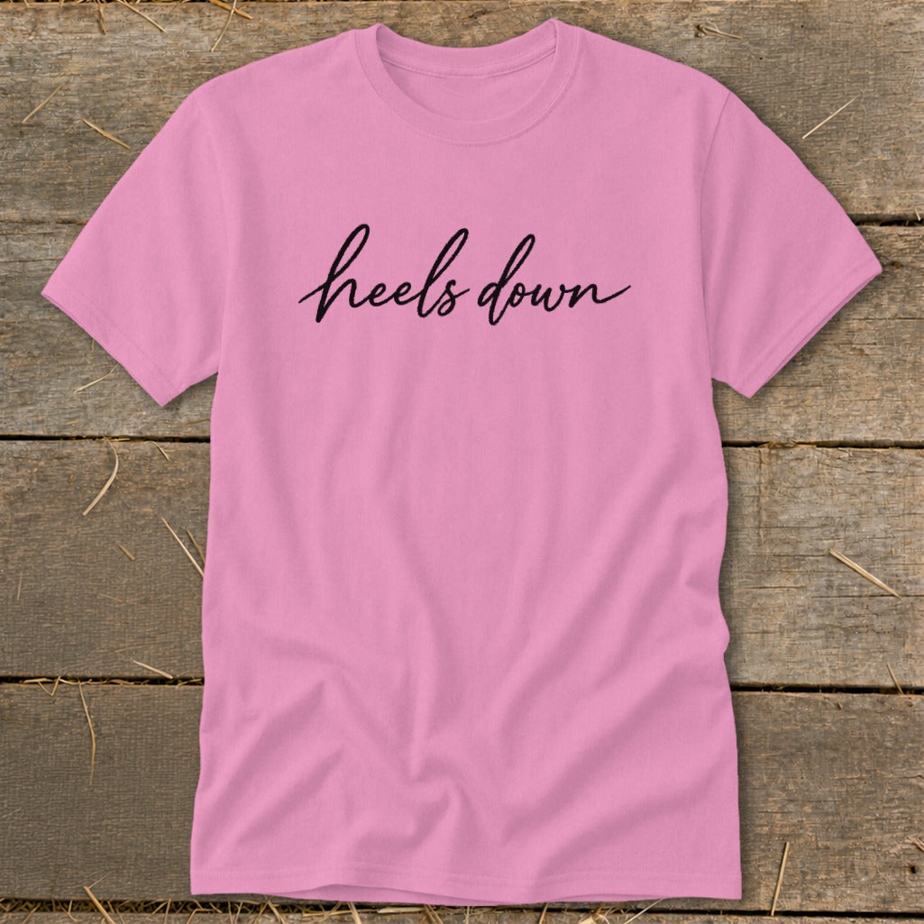 Pink t-shirt with "heels down" text in black cursive font