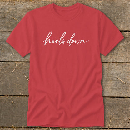 Red t-shirt with white script text that reads "heels down".