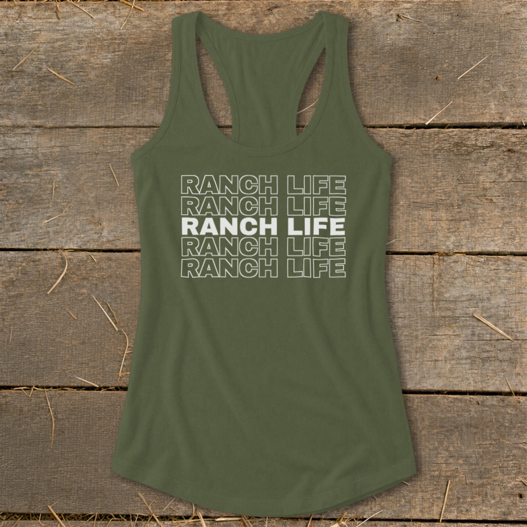 An olive green racerback tank top with the white text "RANCH LIFE" printed in stacked outlines, centered on a rustic wooden background.