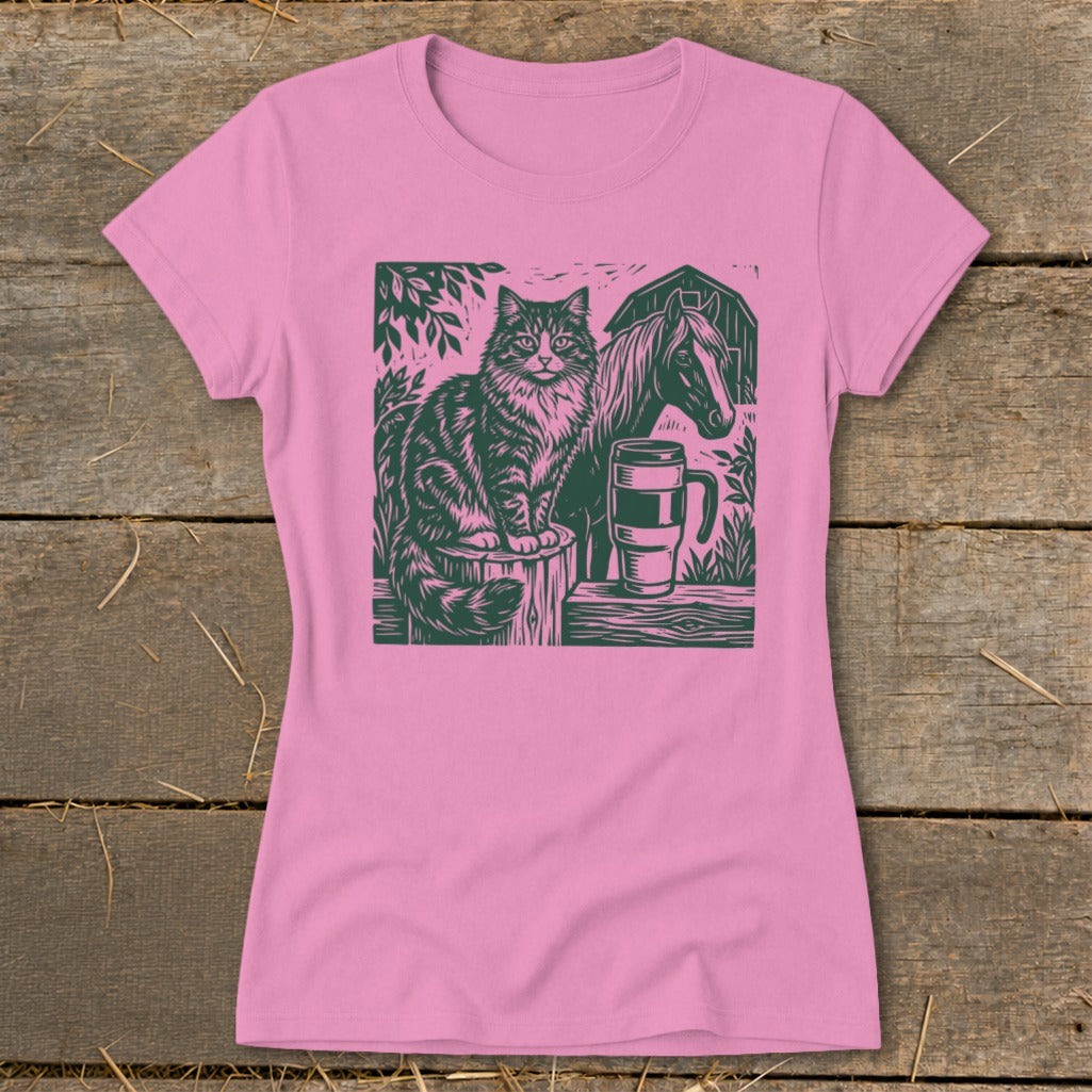 Green linocut of a cat, horse, and coffee mug on a pink t-shirt.