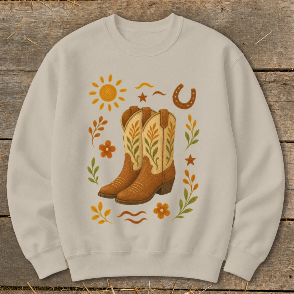 Light tan sweatshirt with cowboy boots, sun, horseshoe, and floral western graphic.