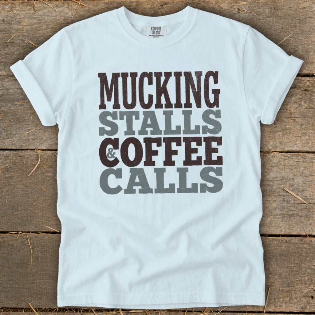 White t-shirt with text MUCKING STALLS & COFFEE CALLS in stacked grey and brown letters.