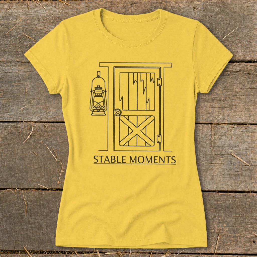 Yellow t-shirt with a line drawing of a barn door and lantern, text reads "STABLE MOMENTS".