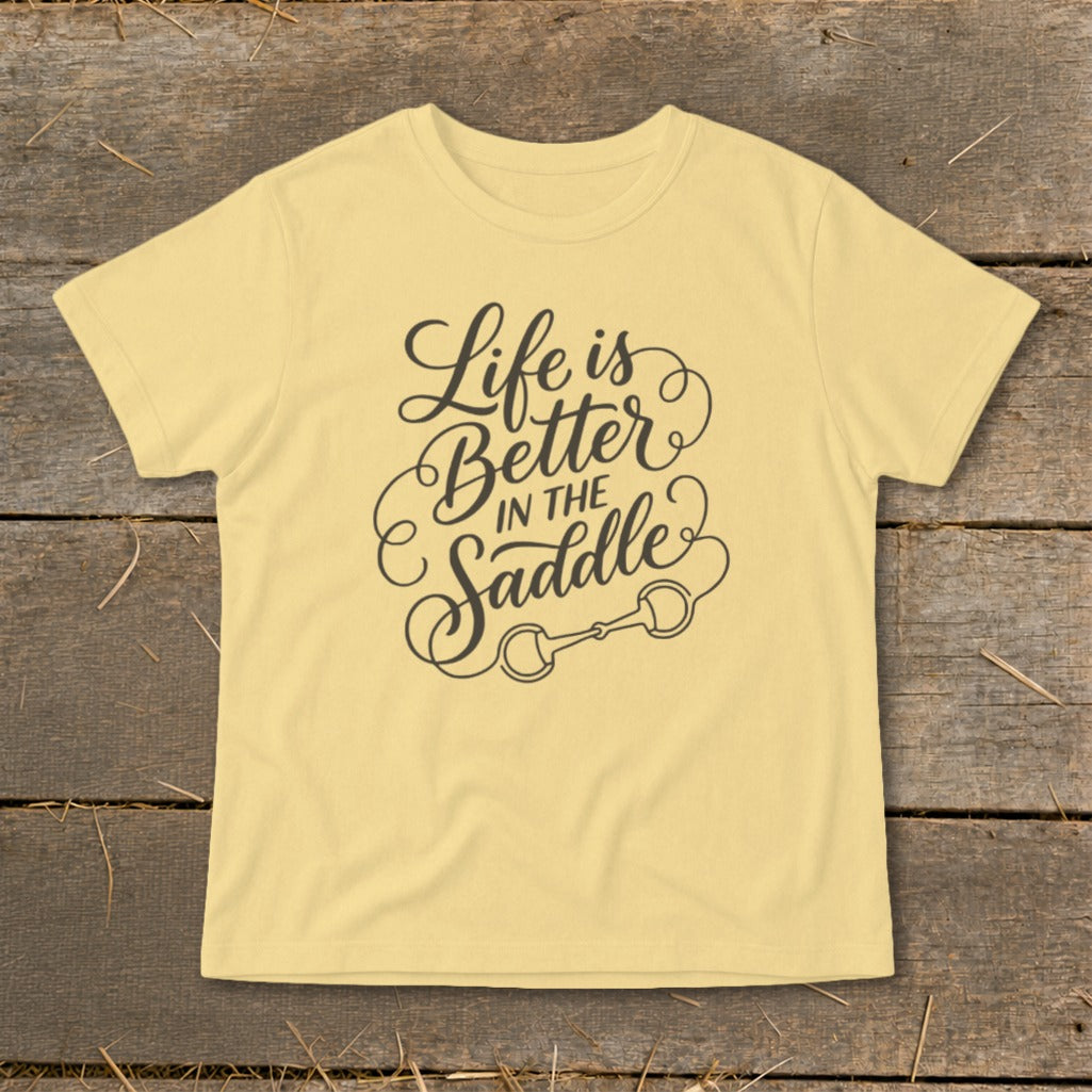 Yellow t-shirt with black text "Life is Better in the Saddle" and horse bit graphic.