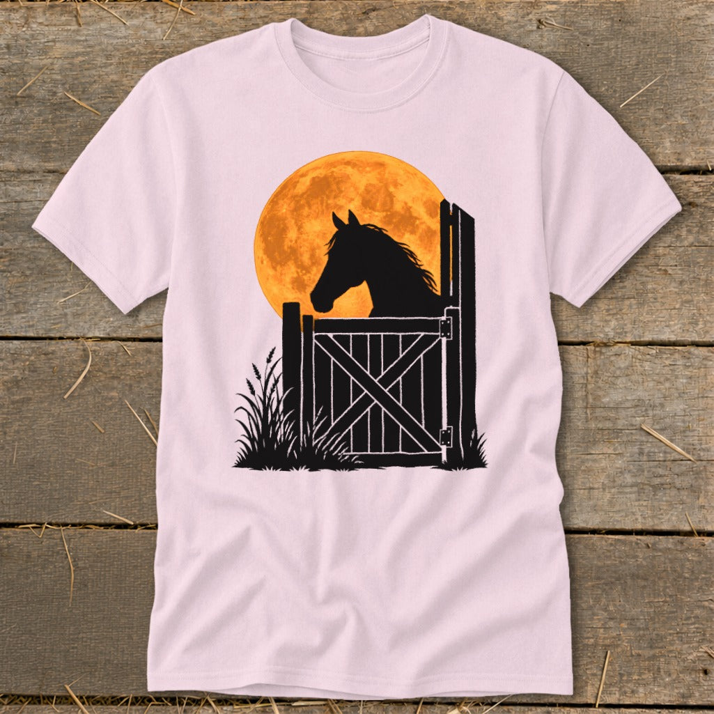 Light pink t-shirt featuring a graphic of a horse silhouette looking over a stable door against a large orange moon.
