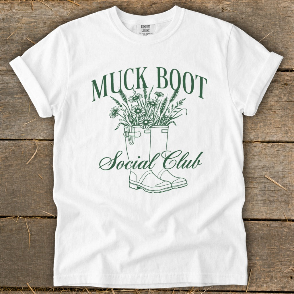 White t-shirt with green "Muck Boot Social Club" text and boot illustration.
