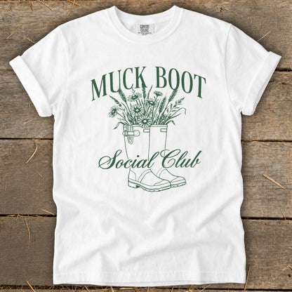 White t-shirt with green "Muck Boot Social Club" text and boot illustration.