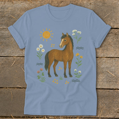 Brown horse surrounded by wildflowers, sun, and wavy lines on a light blue t-shirt.