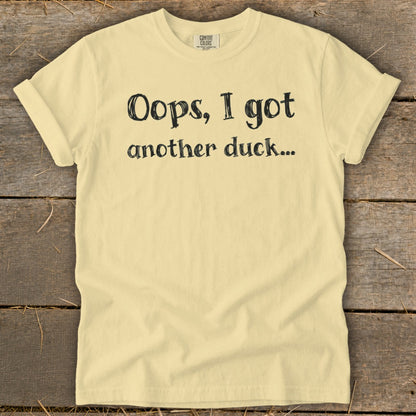 Pale yellow t-shirt with black text that reads "Oops, I got another duck..."