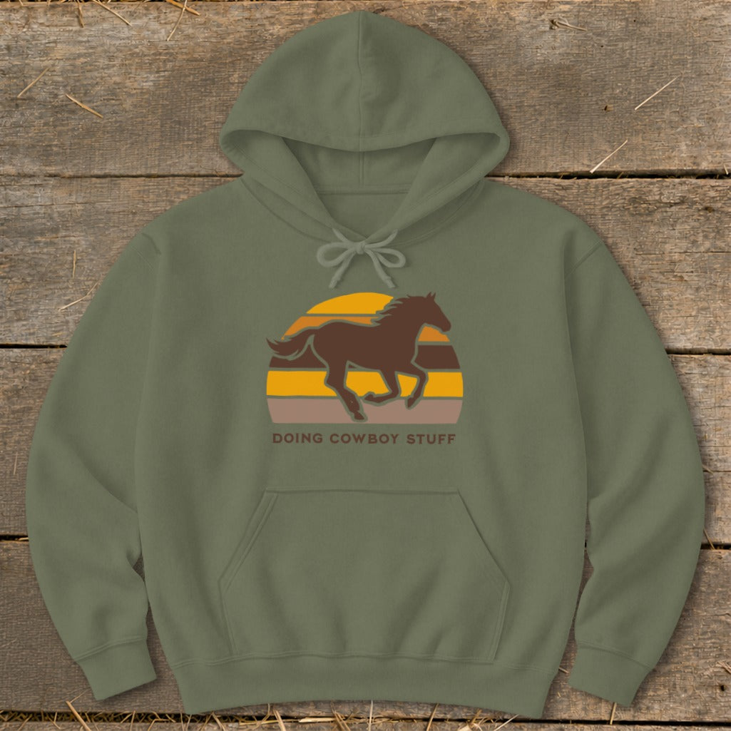 Olive green hoodie with a running horse and sunset graphic and "DOING COWBOY STUFF" text.