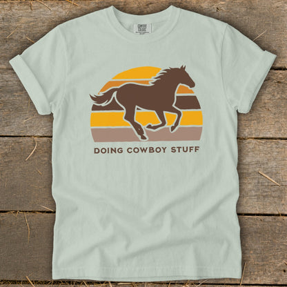 Brown horse silhouette running in front of a sunset with text "DOING COWBOY STUFF".