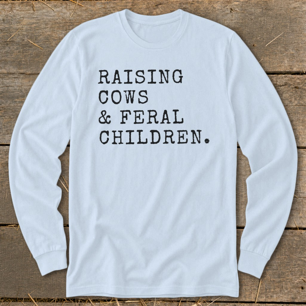 Light blue long-sleeve shirt with black text: Raising Cows & Feral Children.