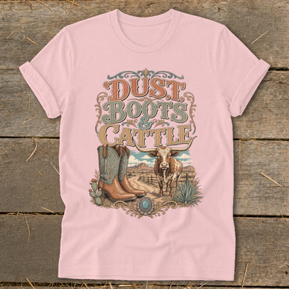 Pink t-shirt print with "Dust Boots & Cattle" text, boots, cow, and desert landscape.