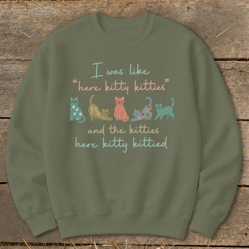 Green sweatshirt with text "I was like 'here kitty kitties' and the kitties here kitty kittied" and cat illustrations.