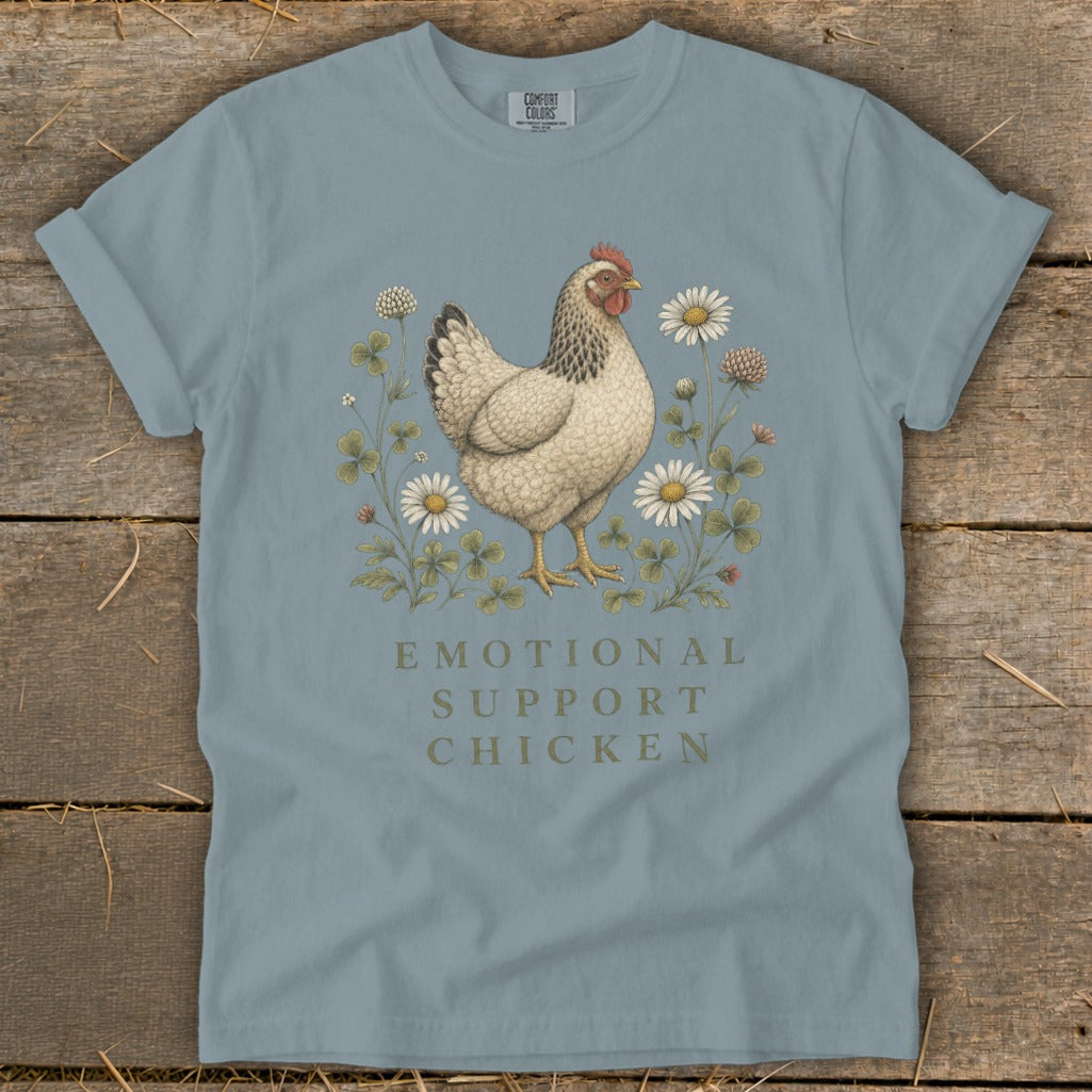 Light blue t-shirt with a chicken, clover, and daisies, reads "Emotional Support Chicken".
