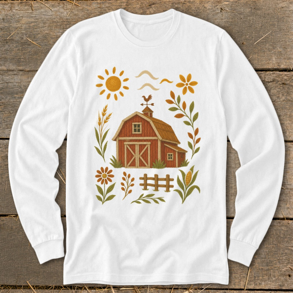 White long sleeve shirt with a rustic farm barn design and sun, flowers, and fence.