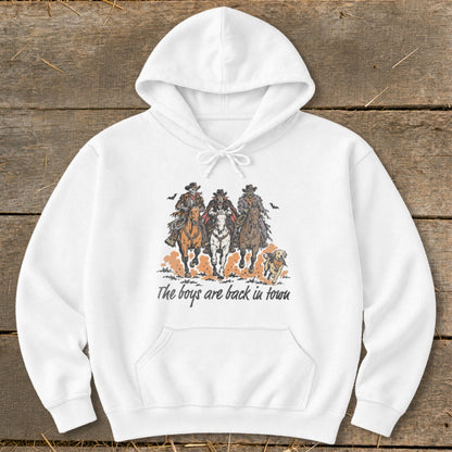 White hoodie with graphic of three skeleton cowboys on horses and a dog, text reads "The boys are back in town."