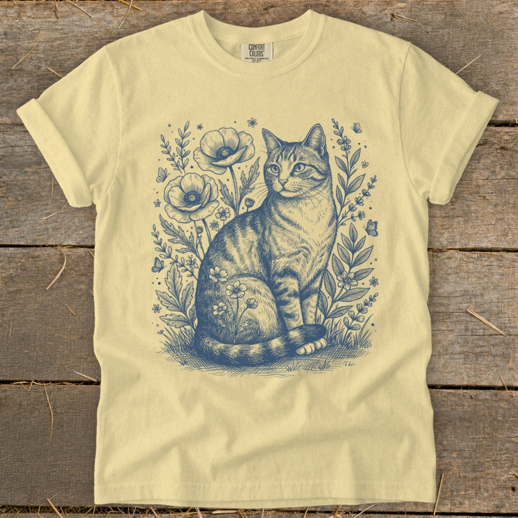 Light yellow t-shirt with a blue ink sketch of a tabby cat among poppies and butterflies.