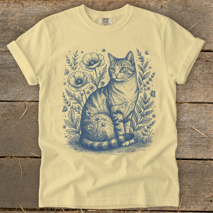 Light yellow t-shirt with a blue ink sketch of a tabby cat among poppies and butterflies.