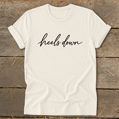 Cream t-shirt with "heels down" text in black script.