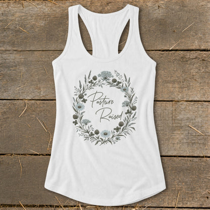 White tank top with "Pasture Raised" text inside a floral wreath.