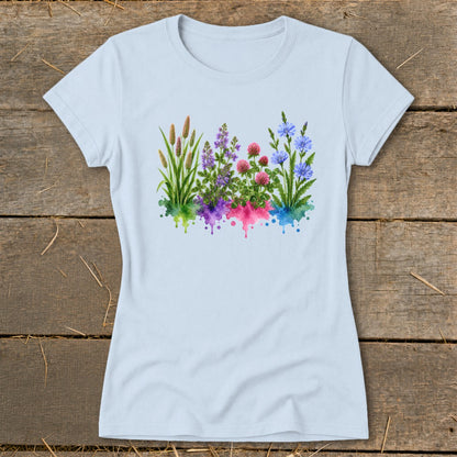 Light blue women's t-shirt featuring a colorful watercolor botanical print of wildflowers on a wooden background.