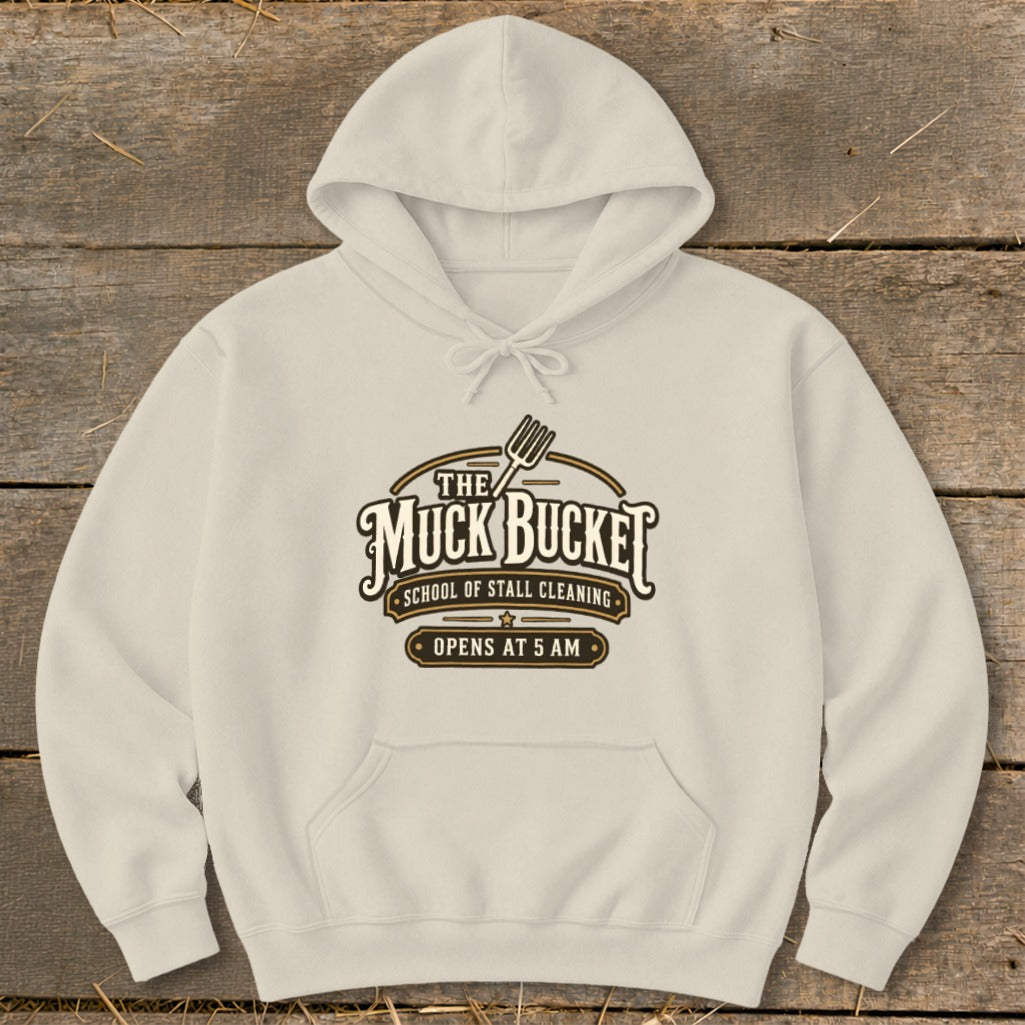 Cream hoodie with "The Muck Bucket School of Stall Cleaning Opens at 5 AM" logo.